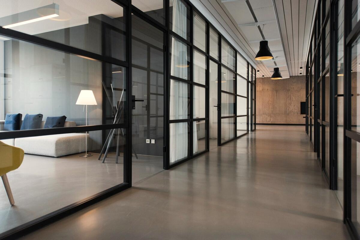 Couloir de bureaux aux cloisons vitrées, en fin de journée